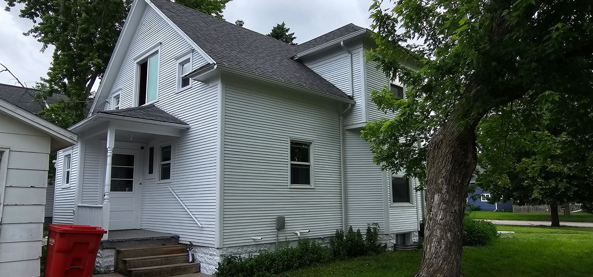 Two-story house with fresh white paint and restored siding after exterior painting project