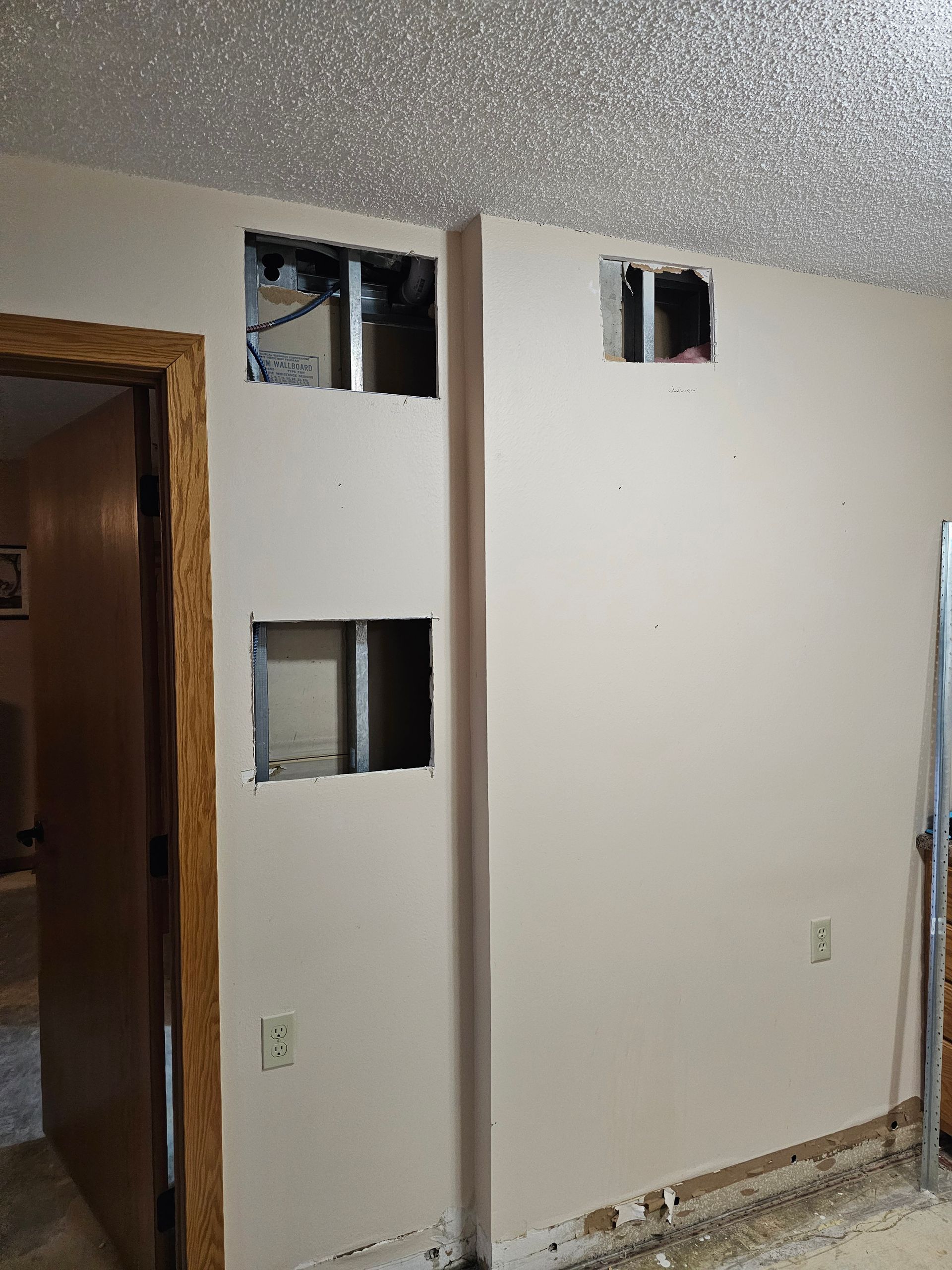 Interior sheetrock wall with holes cut in it before repair