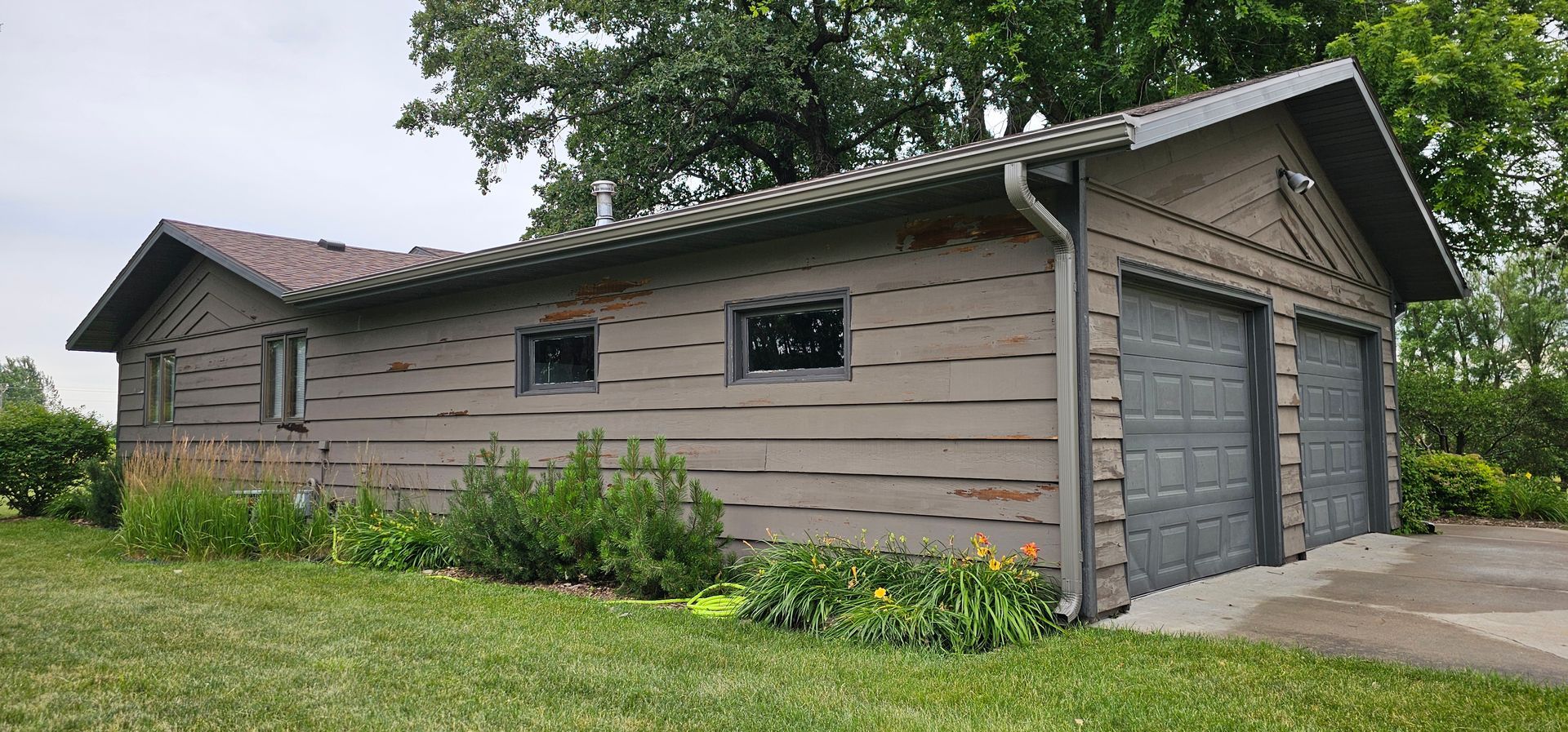 Rural garage with faded brown paint and peeling areas before exterior painting and restoration
