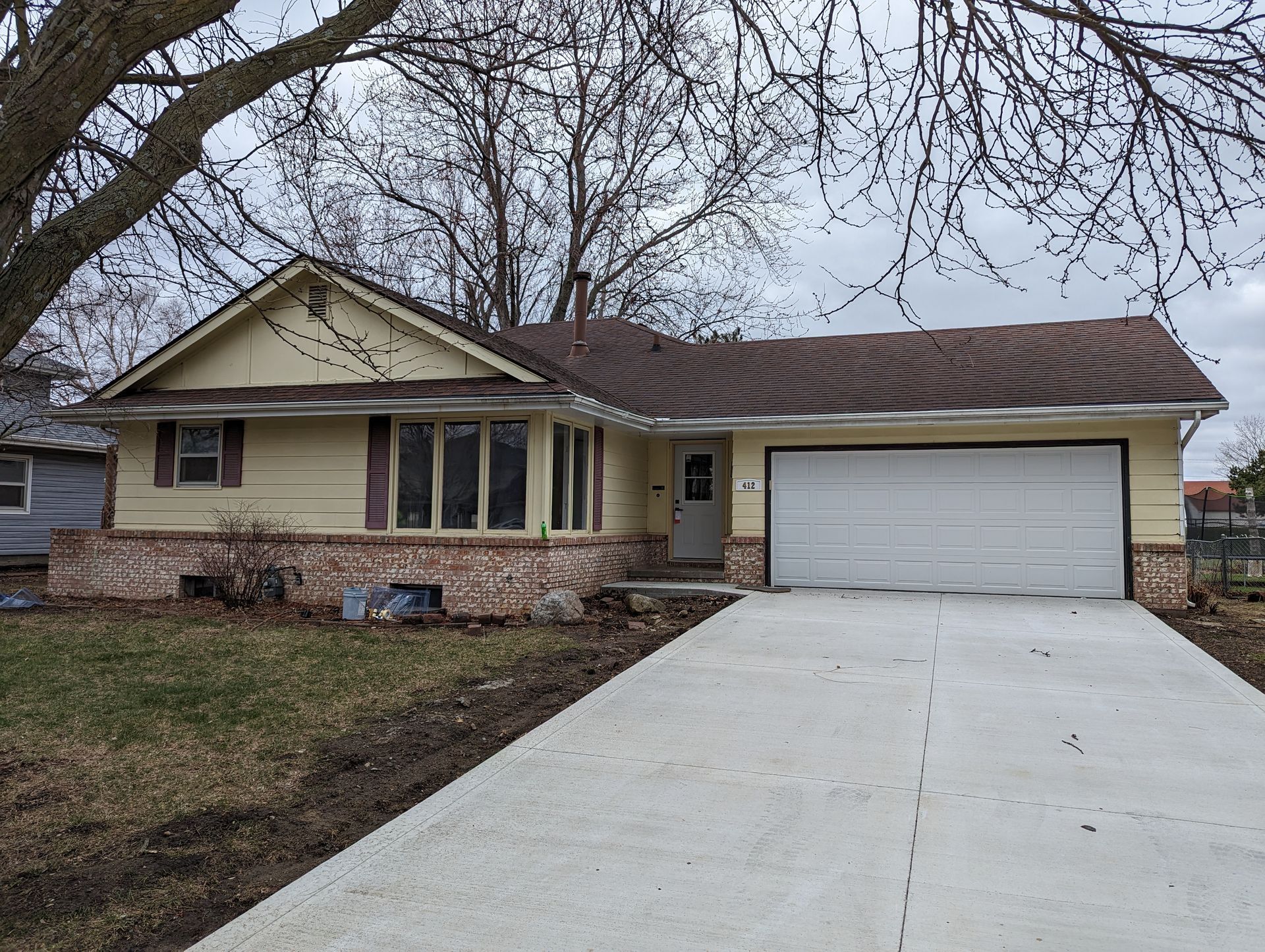 Ranch-style home with faded yellow siding and red brick before exterior painting and renovation