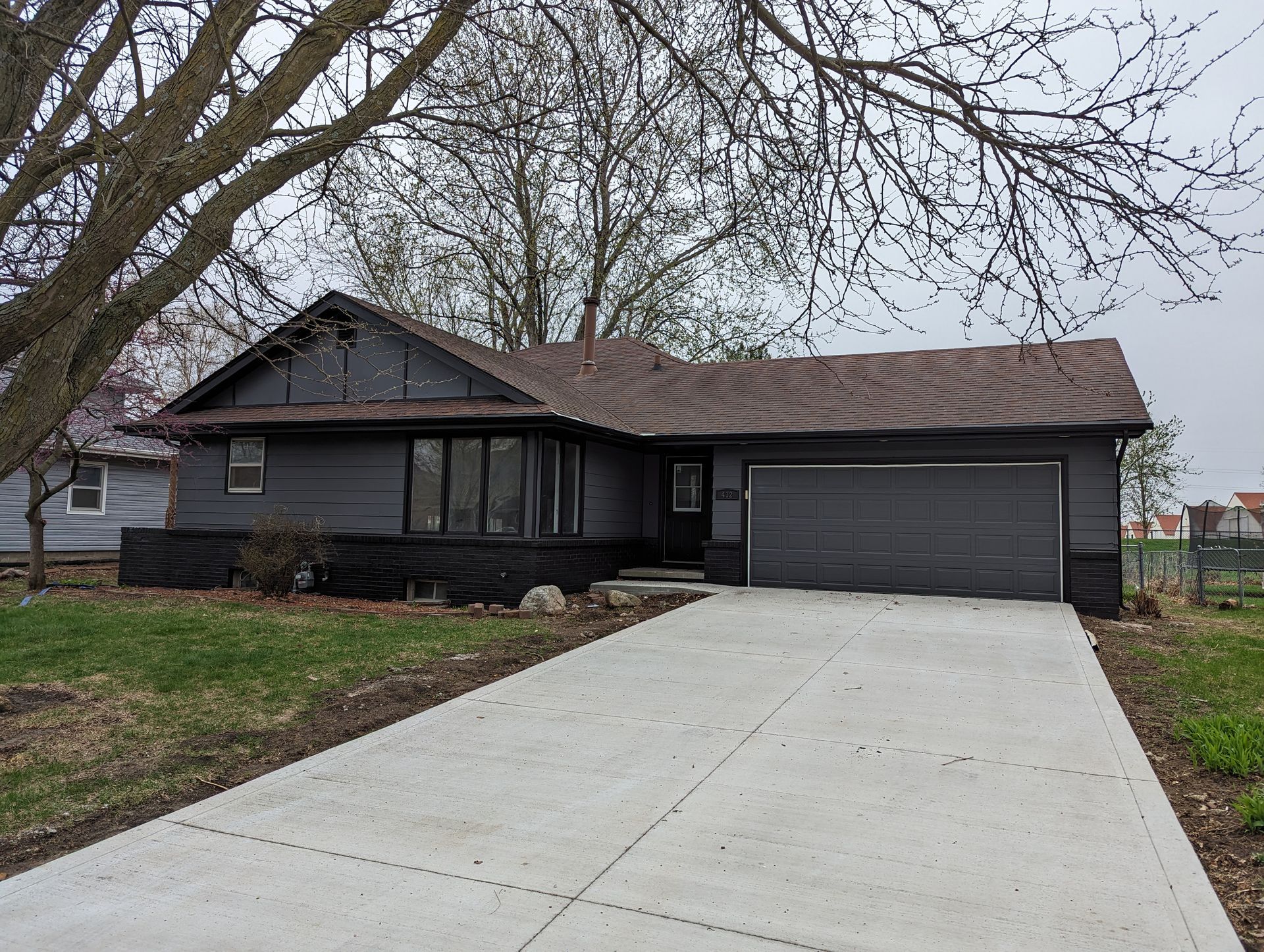 Dark gray ranch-style house with black brick and garage door after dramatic exterior repainting