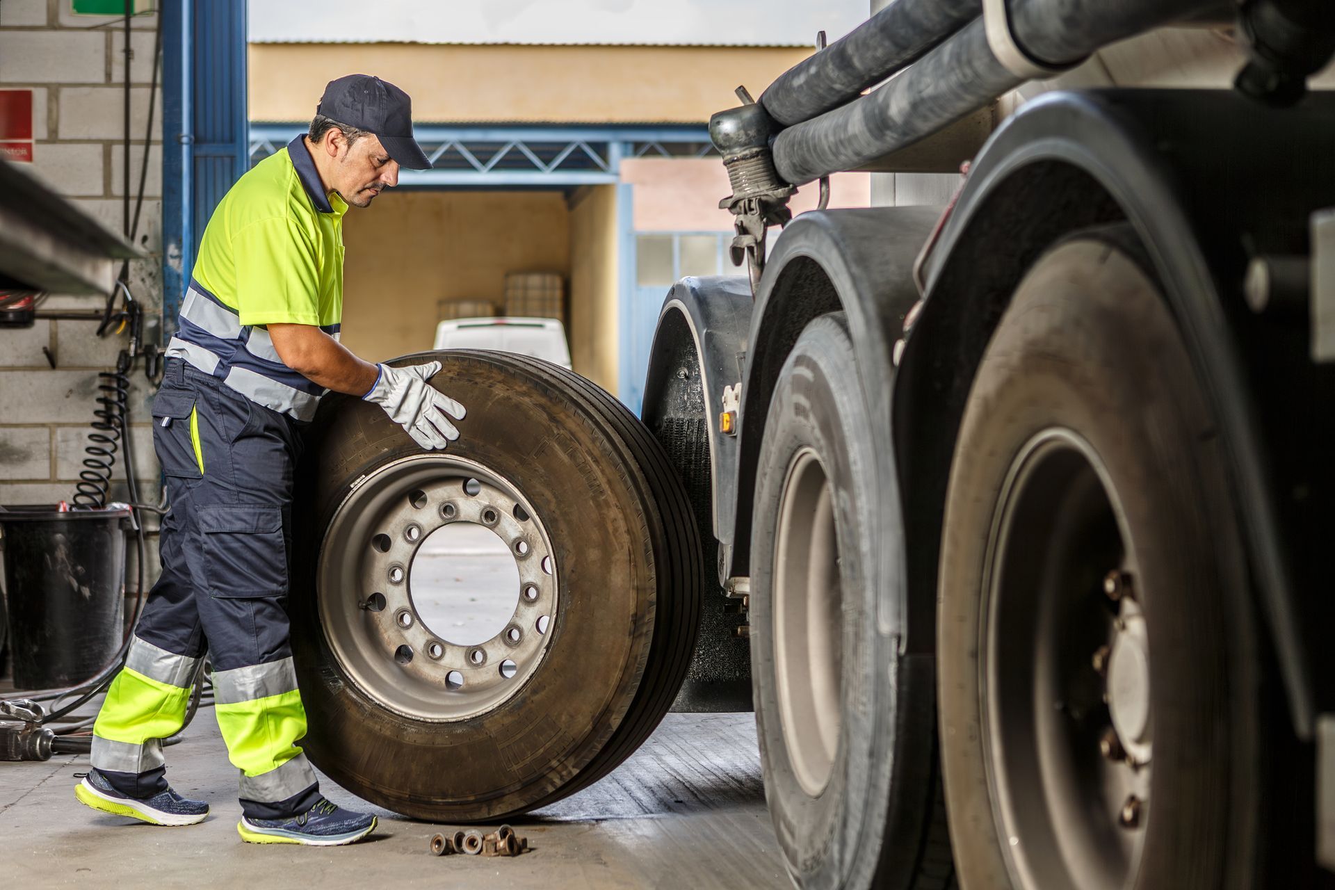 Mechanic performing truck wheel alignment on large vehicle inside a professional repair workshop. Mechanic performing truck wheel alignment on large vehicle inside a professional repair workshop.