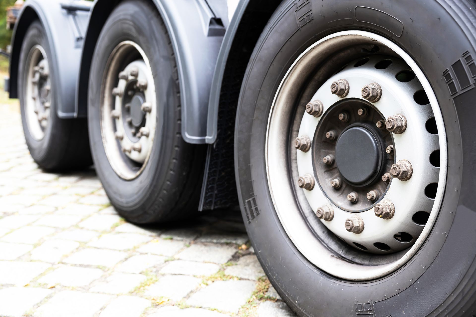 Three large tires of a truck showing signs needing truck wheel alignment for better performance.
