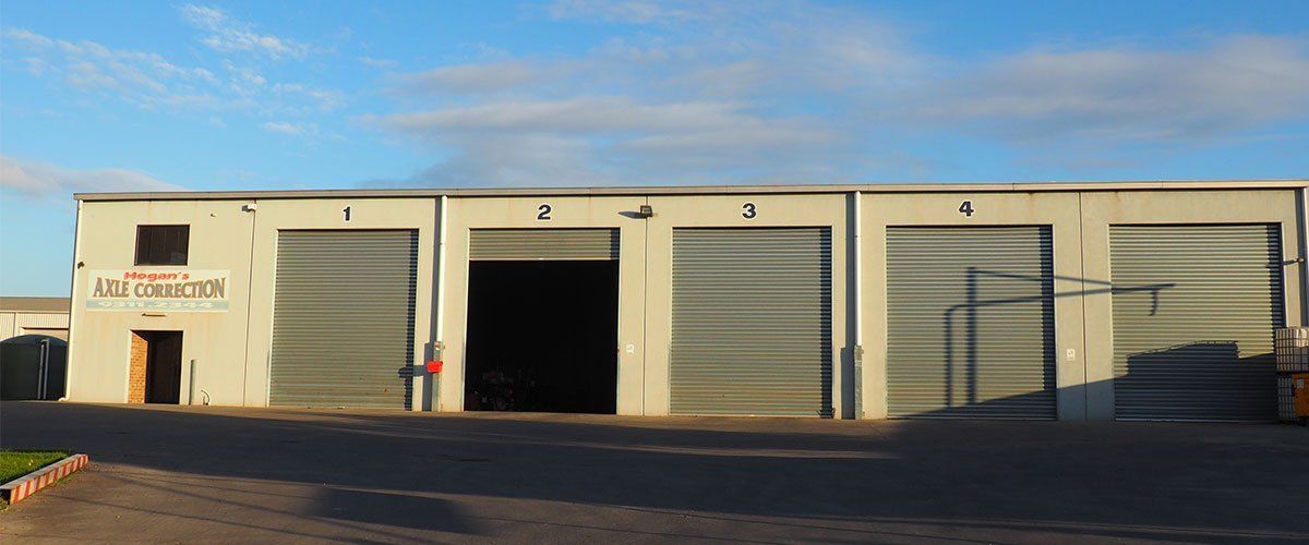 A row of garage bays, numbered, with a partially open door. Buildings are white and grey.