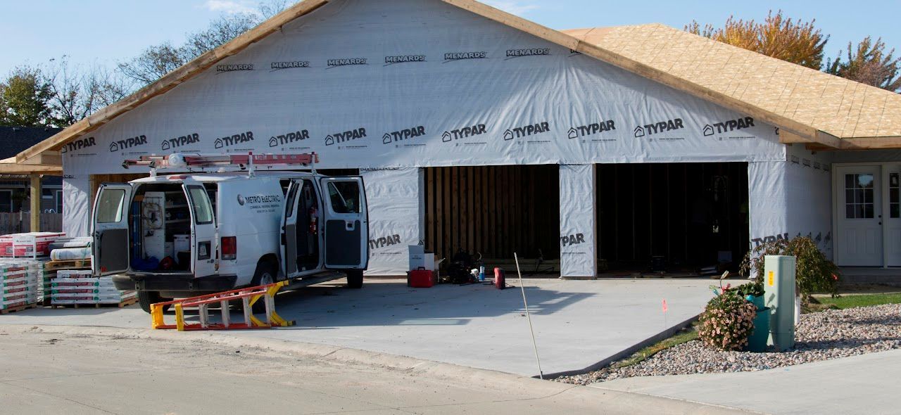 A white van is parked in front of a house under construction.