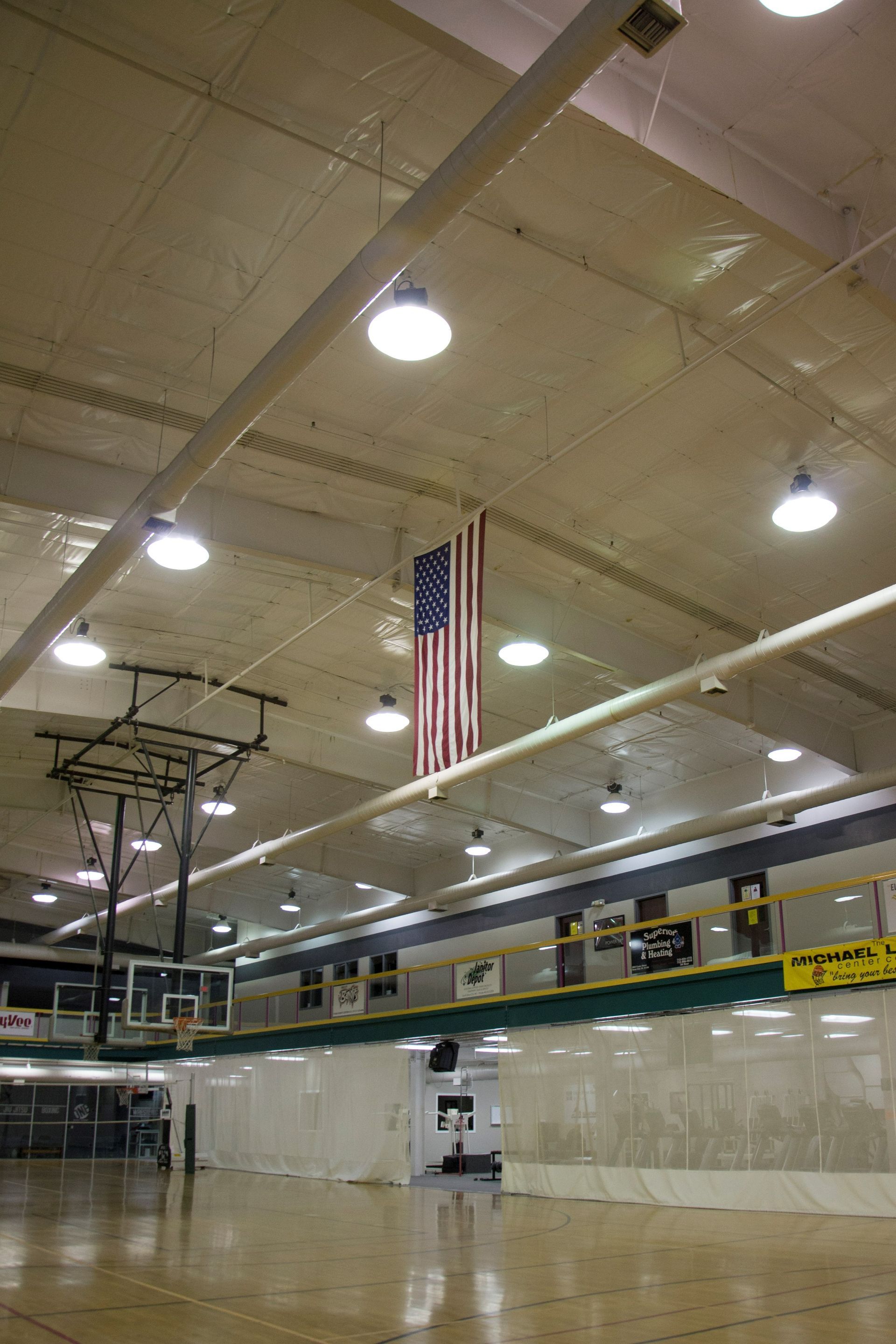 A basketball court with an american flag hanging from the ceiling