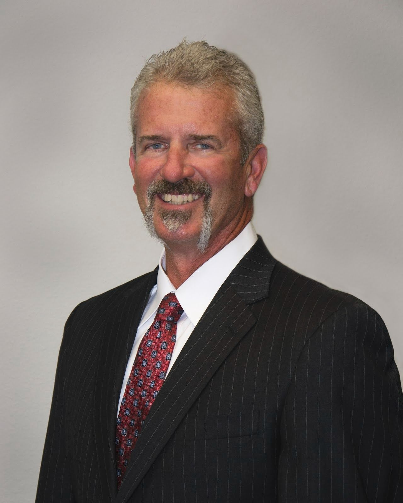 A man in a suit and tie is smiling for the camera