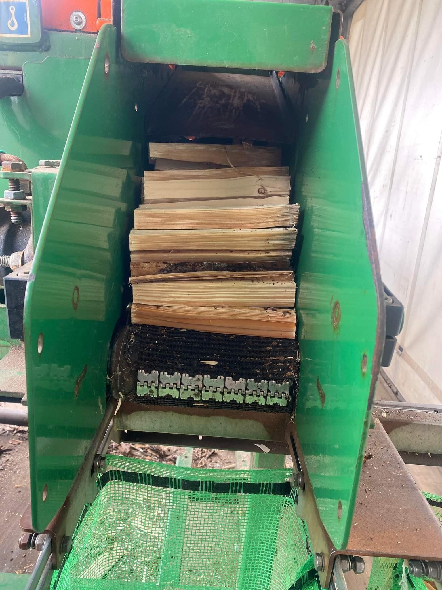 A green machine is cutting wood into pieces.