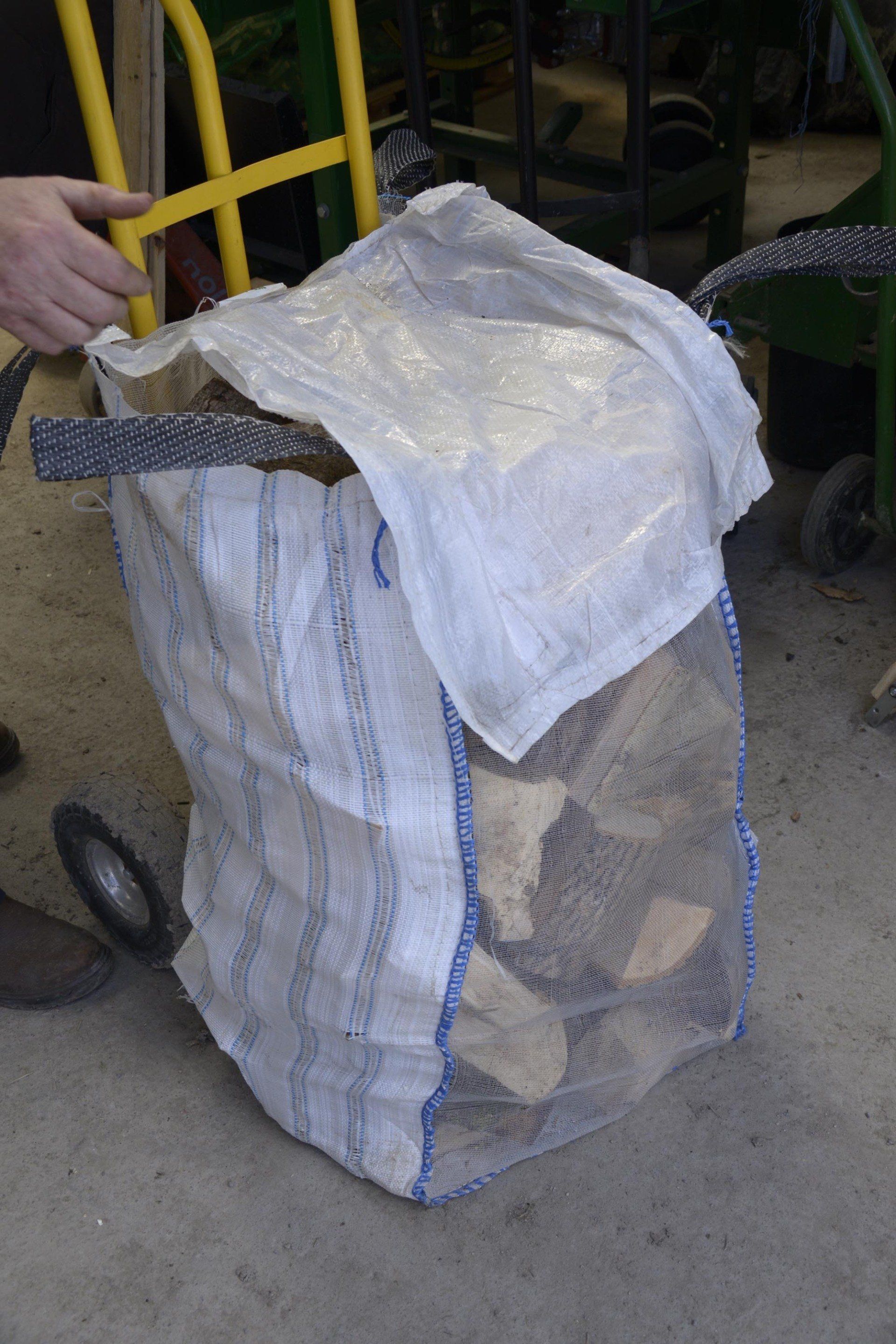 A person is carrying a bag of logs on a cart.