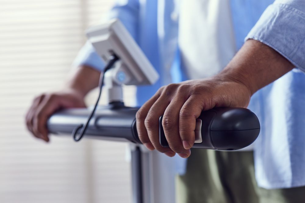 Person’s hands on a treadmill console in a gym, adjusting settings.