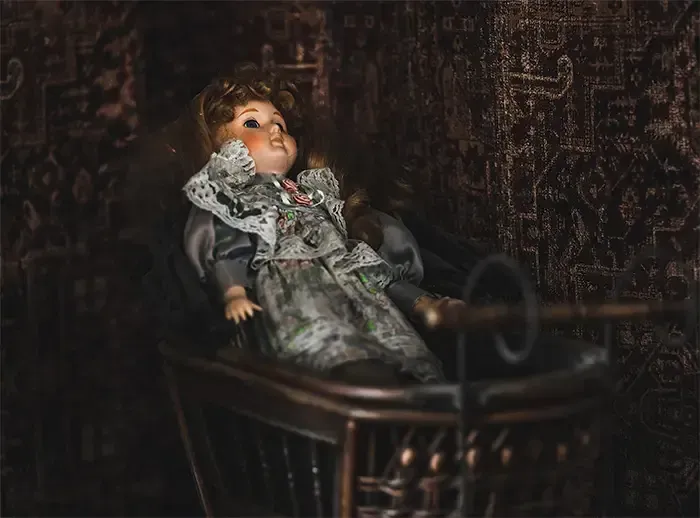 Een pop zit op een stoel in een donkere kamer.