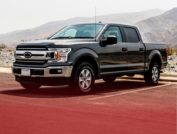 A black pickup truck is parked in a parking lot with mountains in the background. | White Sulphur Garage