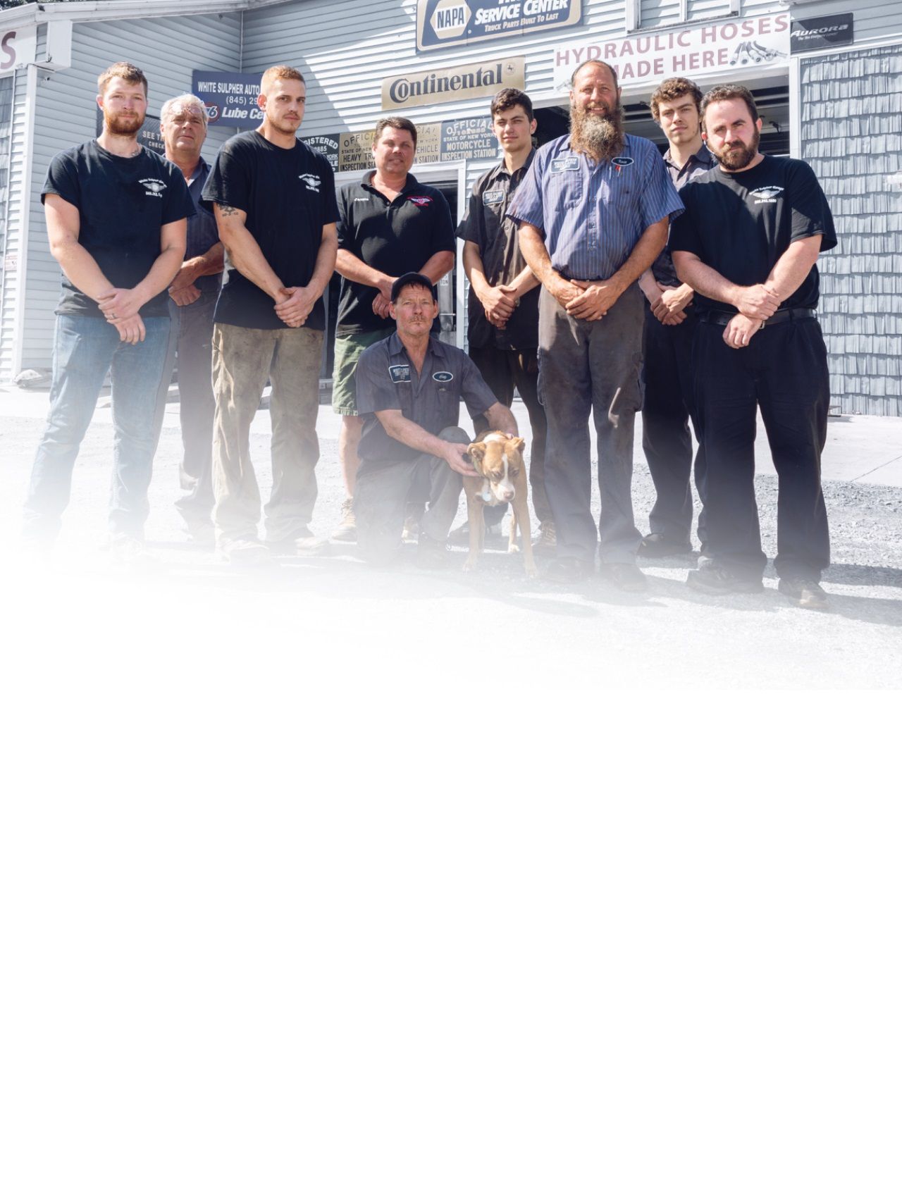 A group of men are posing for a picture in front of a building. | White Sulphur Garage