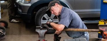 A man is working on a tire in a garage. | White Sulphur Garage