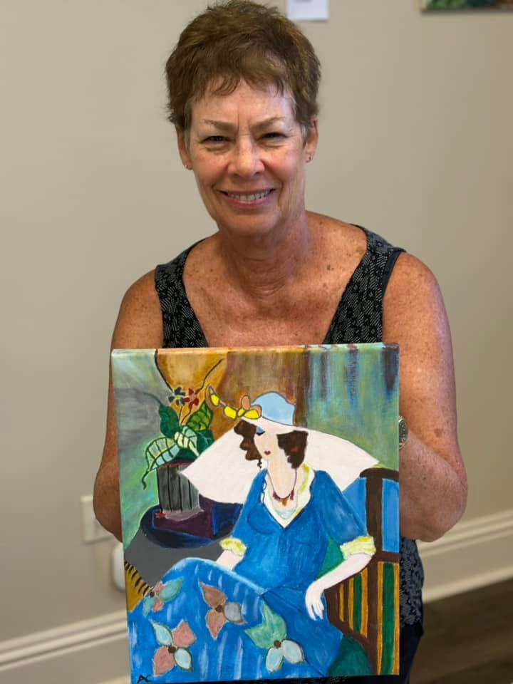 A woman is holding a painting of a woman in a blue dress
