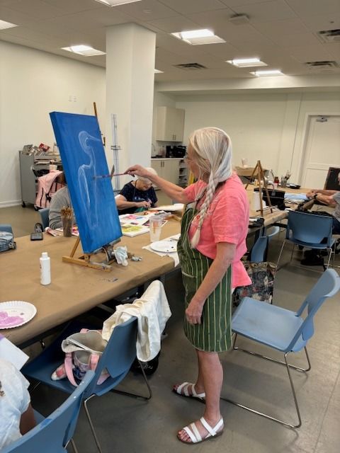 A woman is painting a picture on an easel
