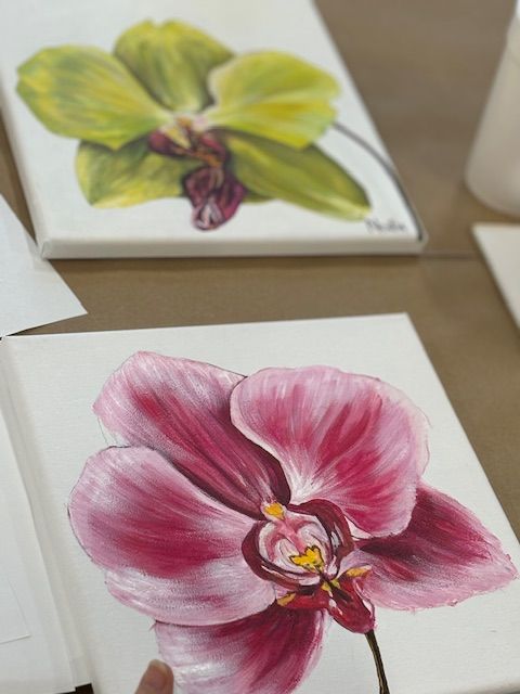 A person is holding a painting of a pink flower