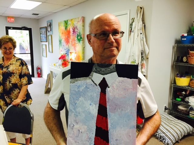A man is holding a painting of a shirt and tie