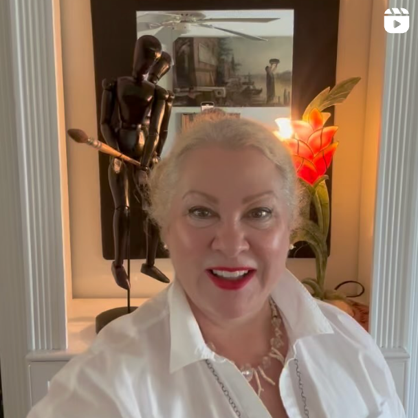 A woman in a white shirt is smiling in front of a statue