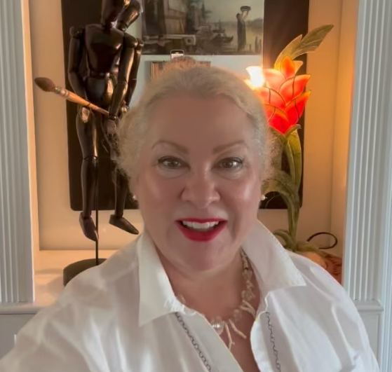 A woman in a white shirt is smiling in front of a statue