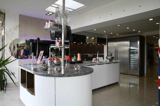 A kitchen showroom showing a large kitchen counter with large steel fridges and a grey marble worktops