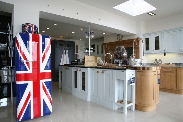 A kitchen showroom with a large union jack fridge with a multiple style kitchens surfaces in the background showing the many types of products Kitchen House supply and fit.