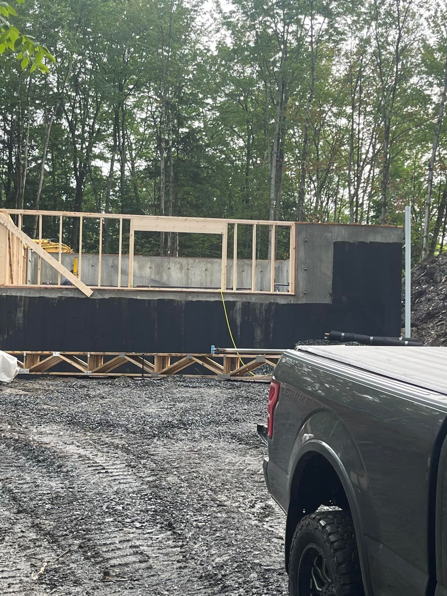 Fondations partiellement construites avec ossature en bois, membrane d'étanchéité noire.