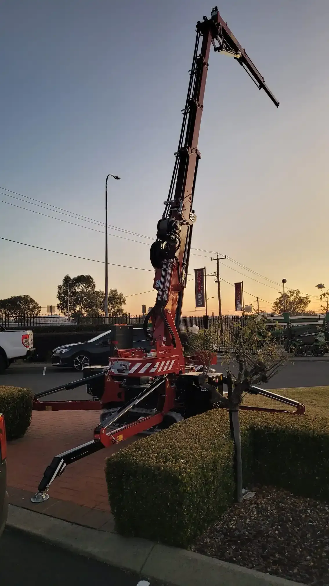 Red aerial lift extended at sunset.