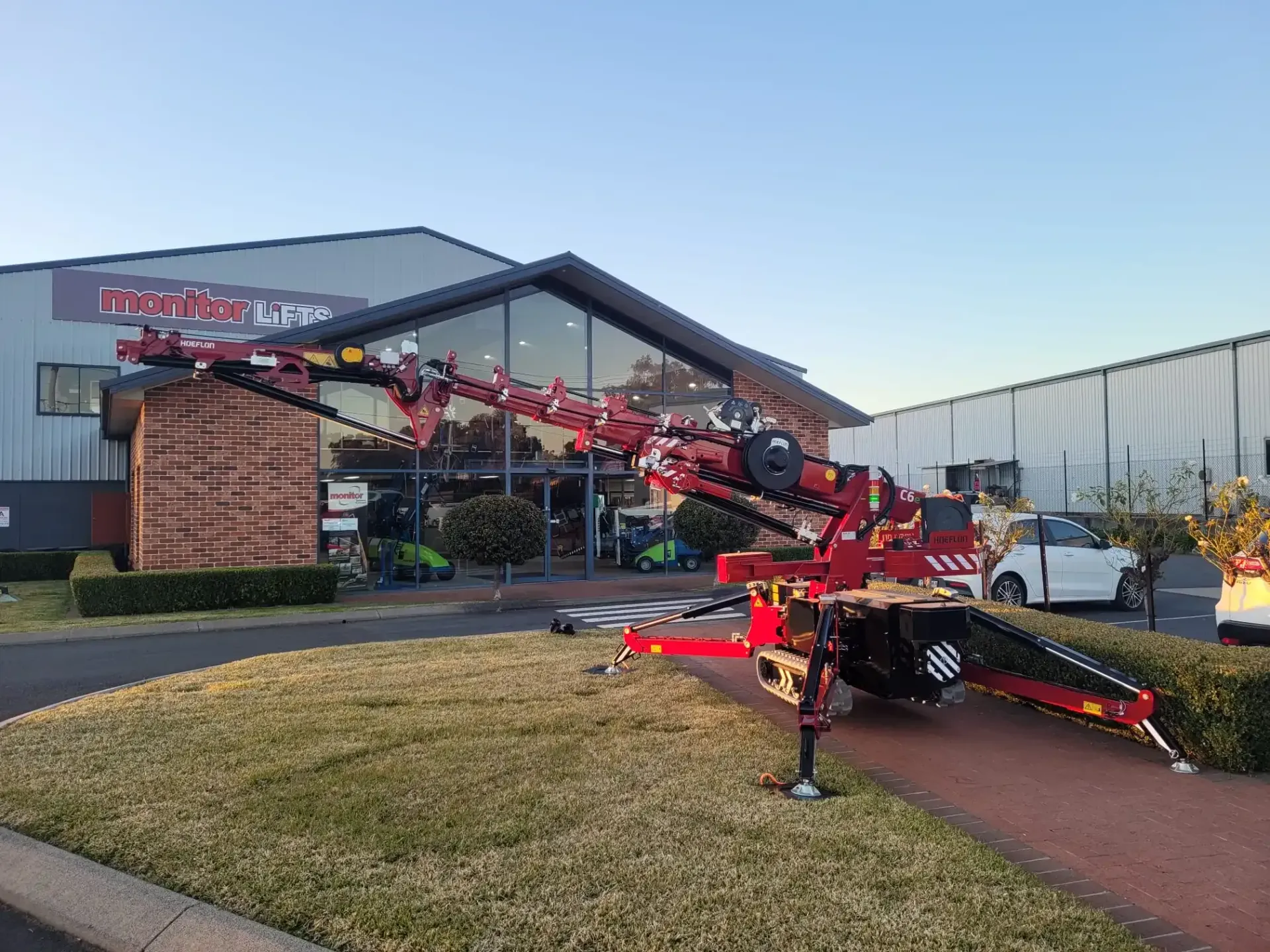 Red crane extending towards a building with broken windows; grassy area in front.