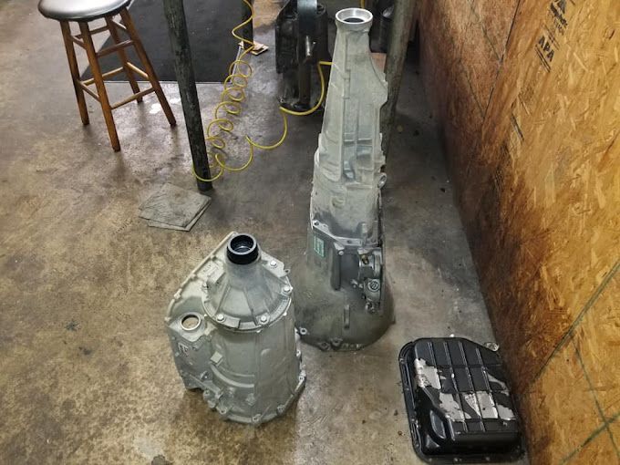 Three gearboxes are sitting on the floor in a garage.