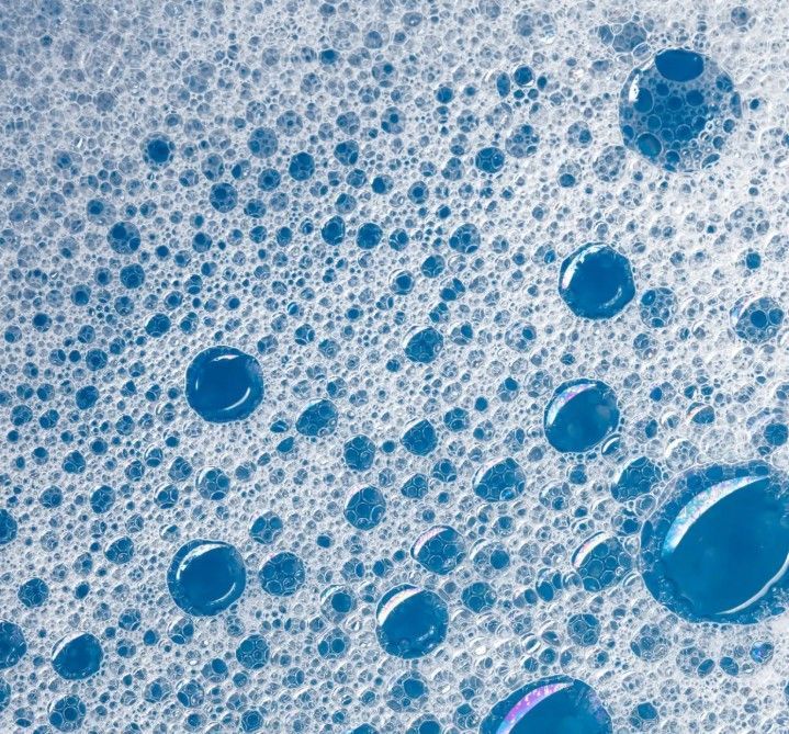 Person spraying a plant with a spray bottle next to pruning shears.