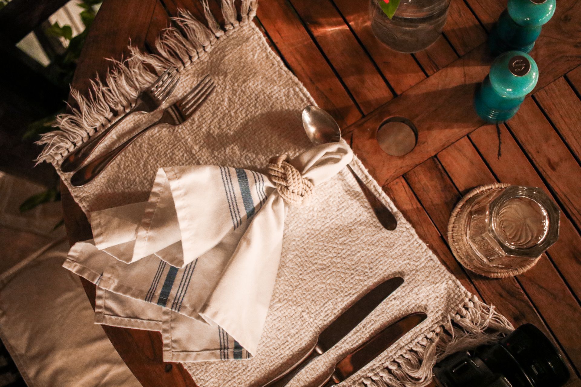 A wooden table with a napkin and silverware on it.