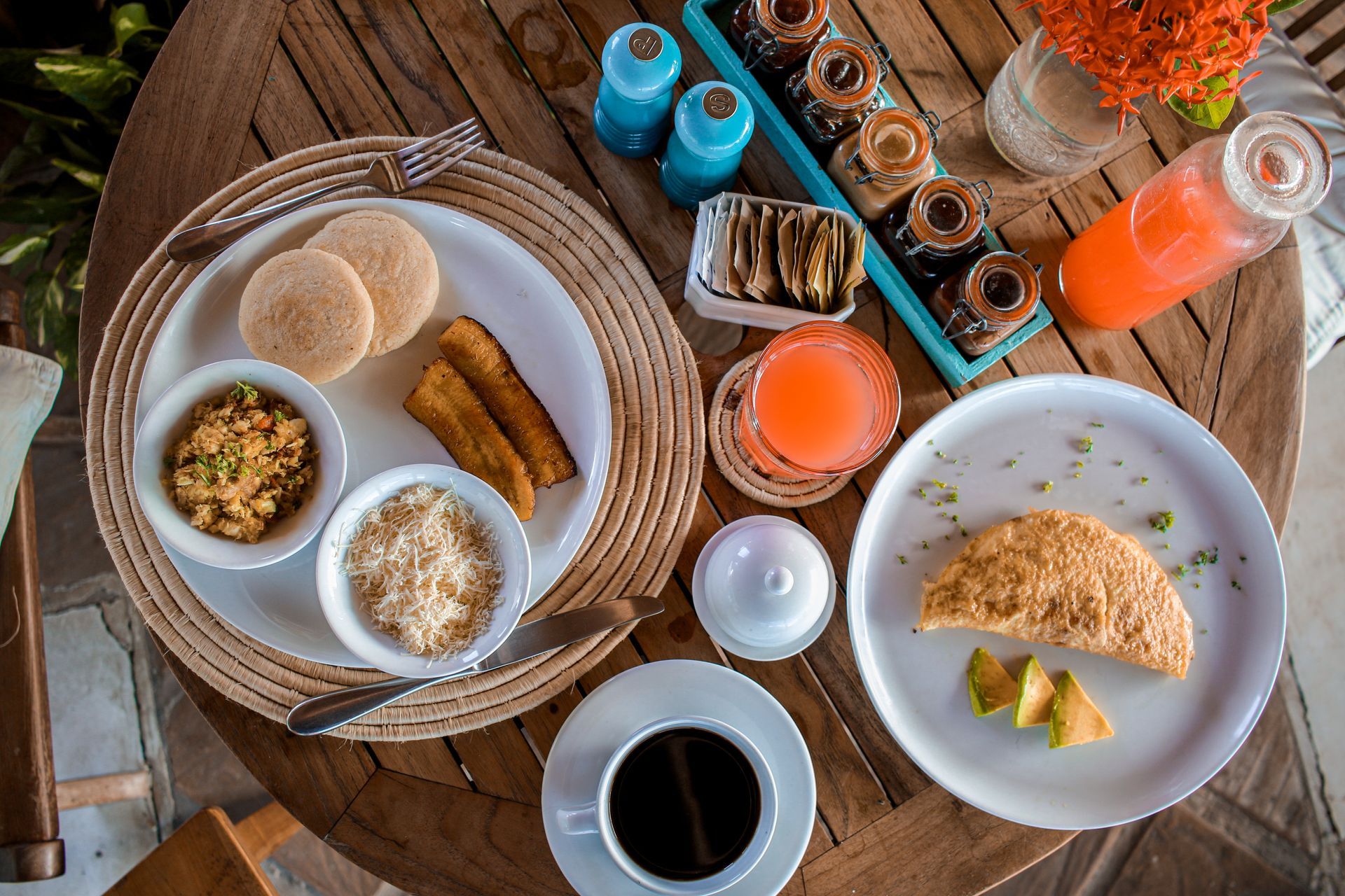 A wooden table topped with plates of food and drinks.