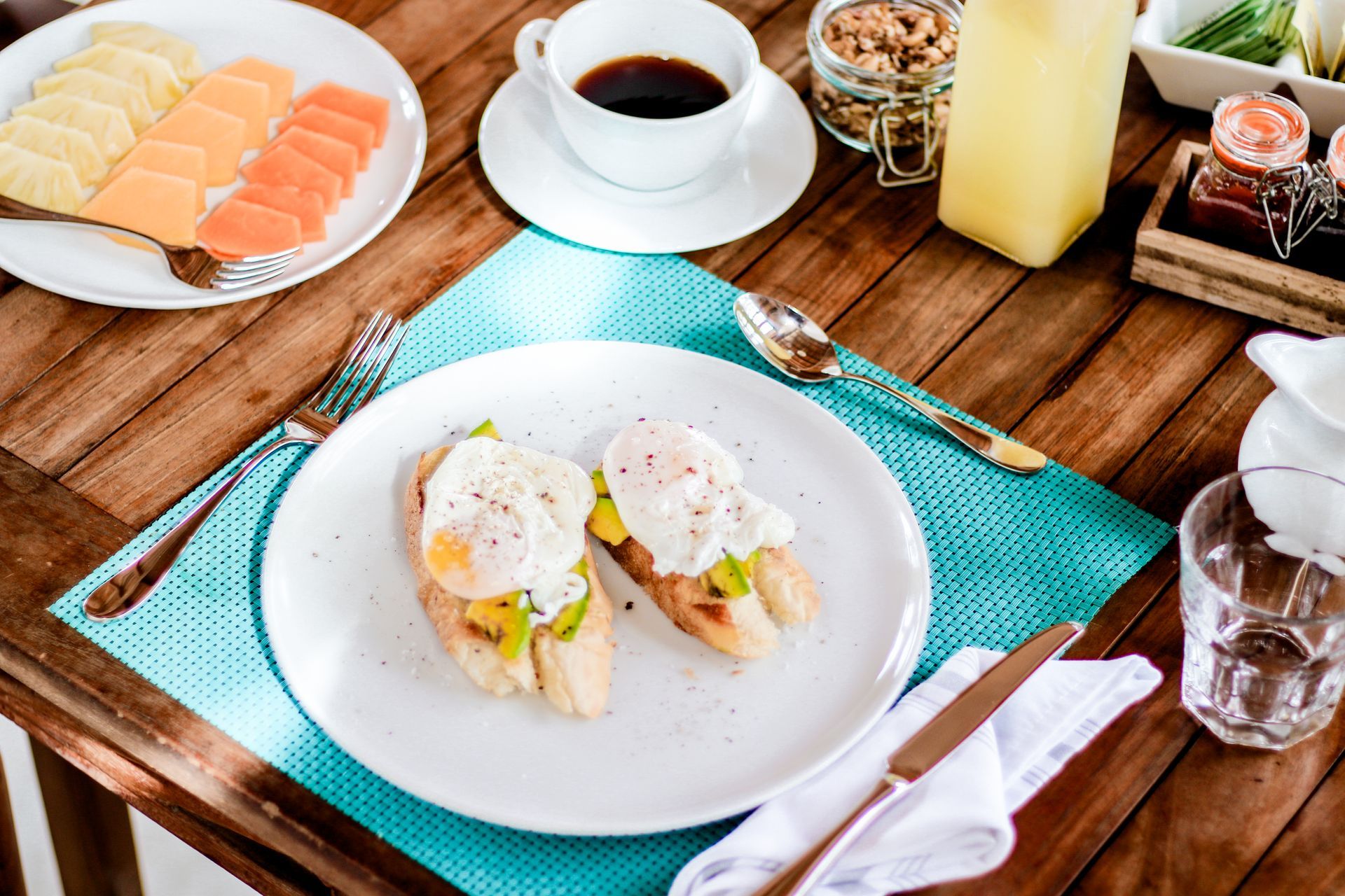 A wooden table topped with plates of food and a cup of coffee.
