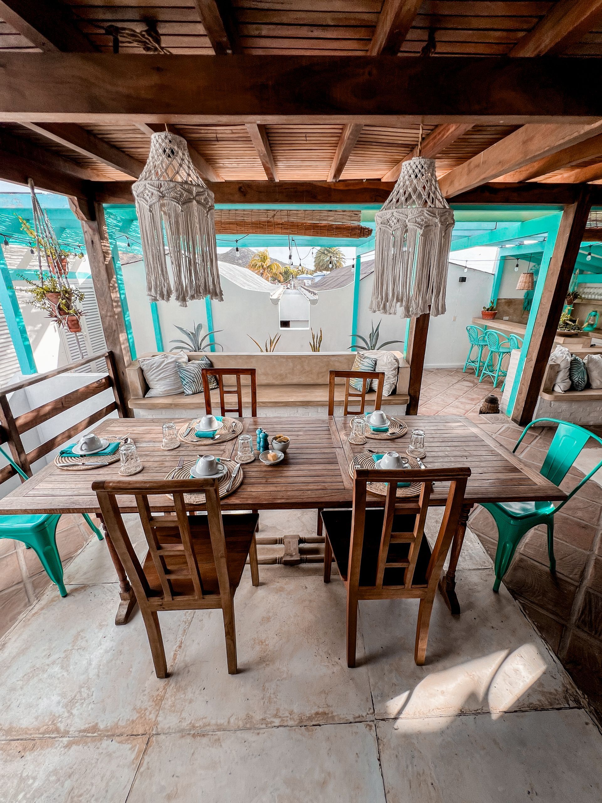 A dining room with a wooden table and chairs under a wooden roof.
