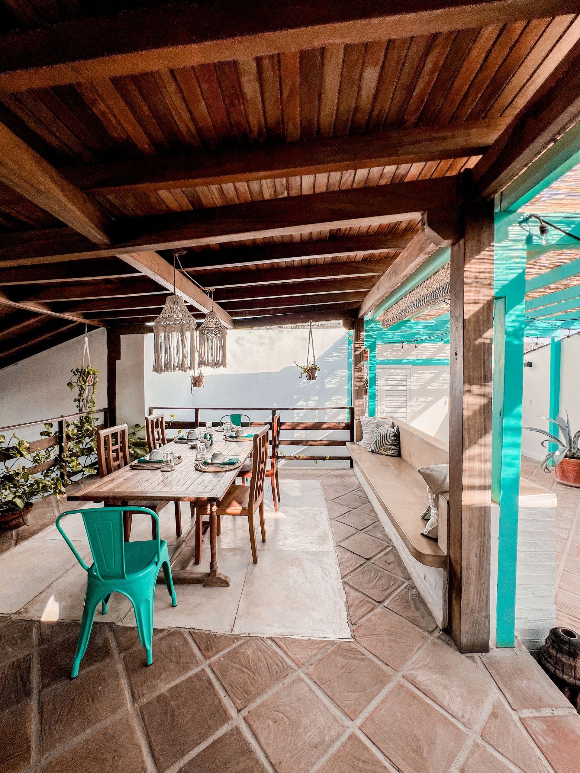 A patio with a table and chairs under a wooden roof.