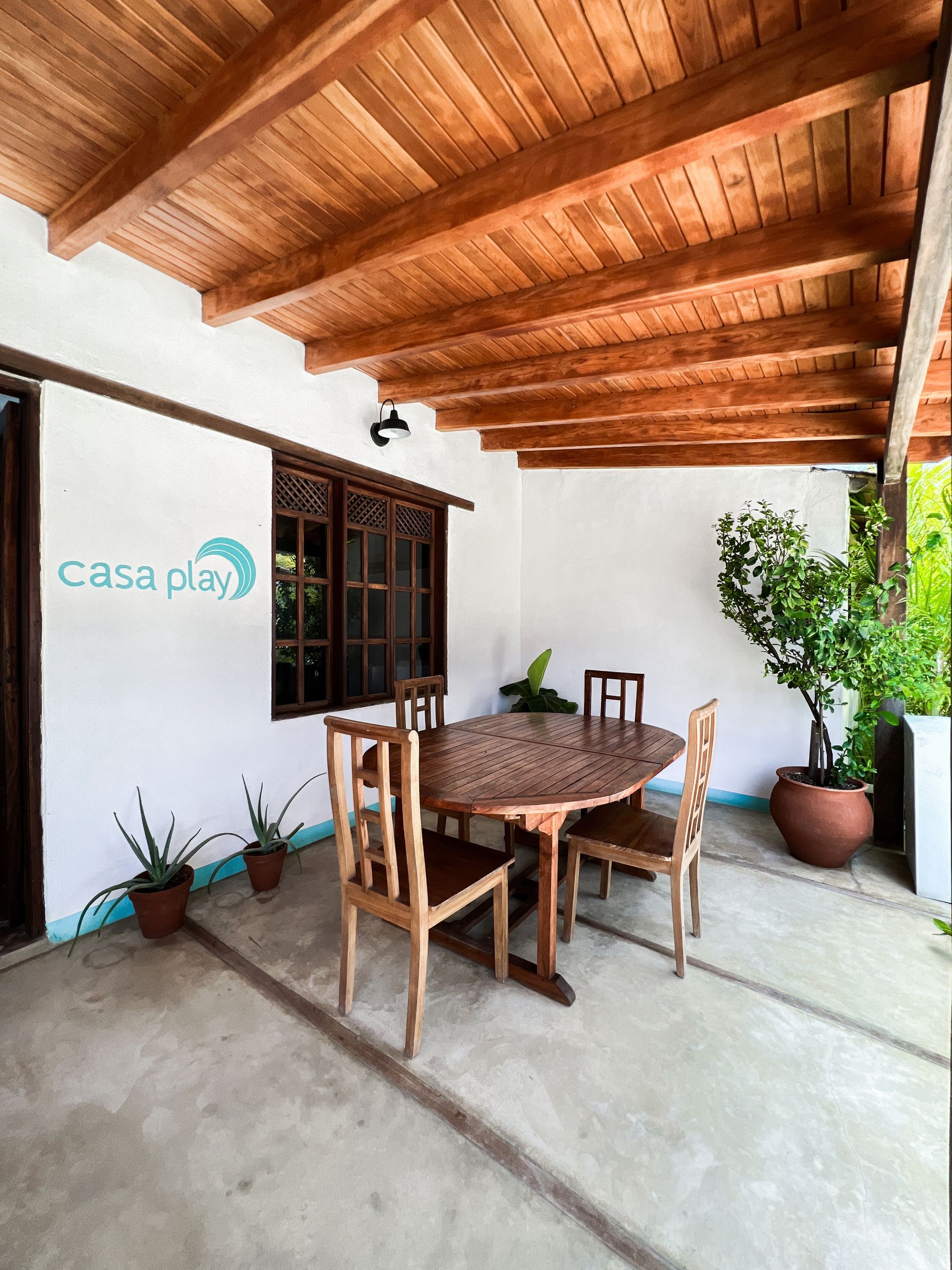 A patio with a table and chairs under a wooden ceiling