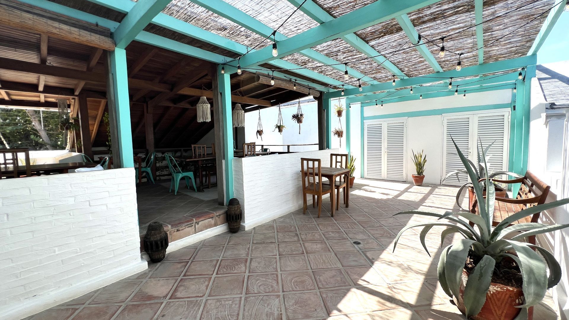 A patio with tables and chairs under a blue roof.