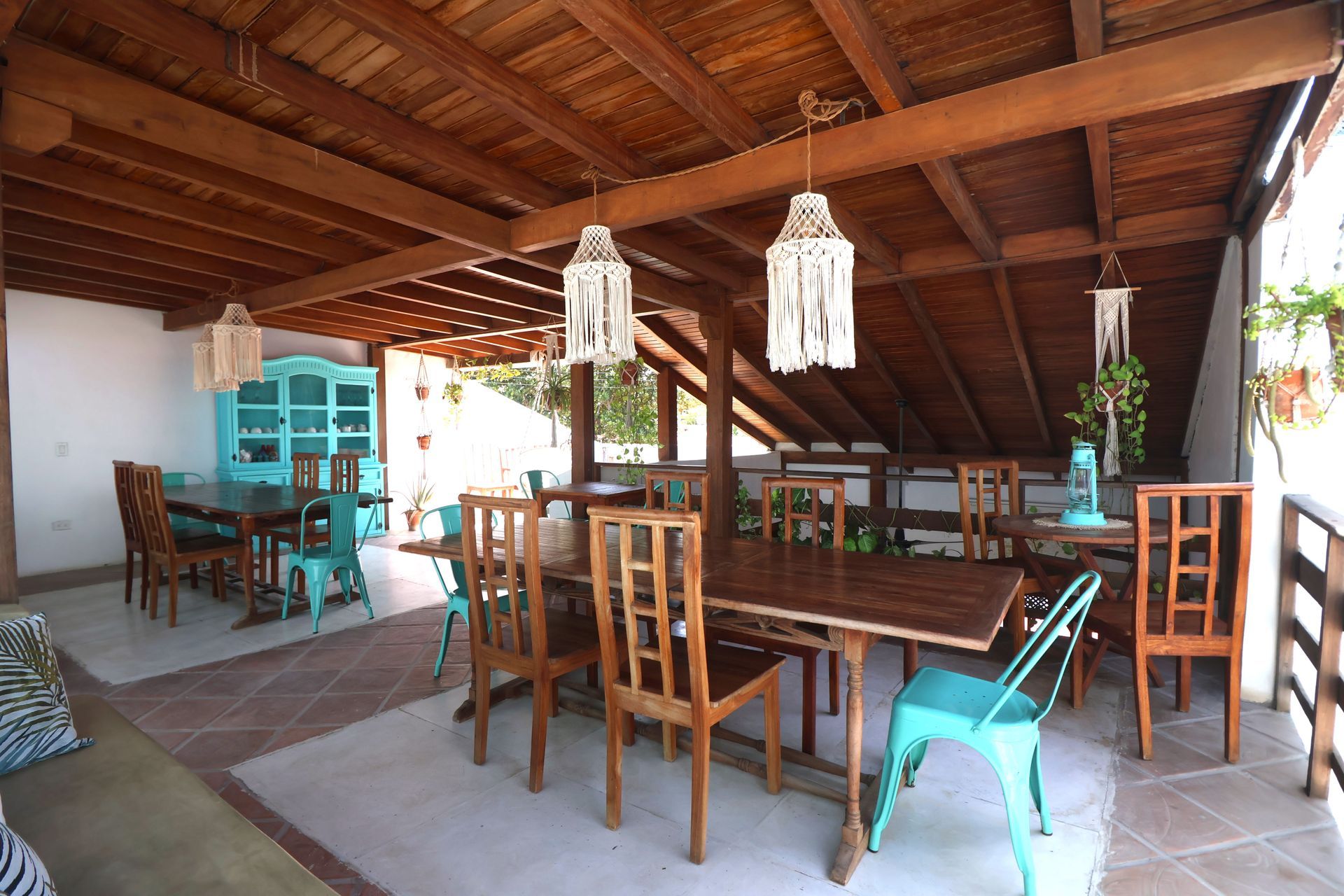 A dining room with tables and chairs under a wooden roof