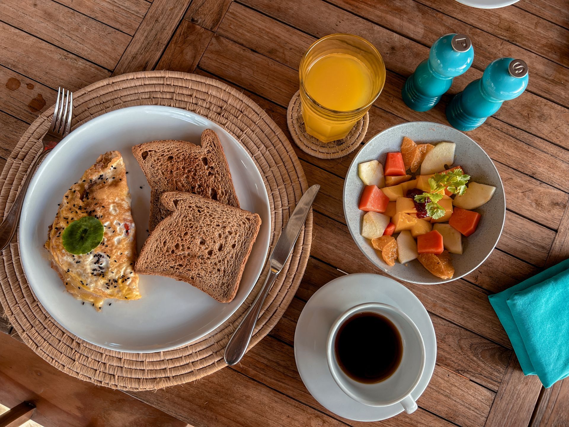 A wooden table topped with plates of food and a cup of coffee.
