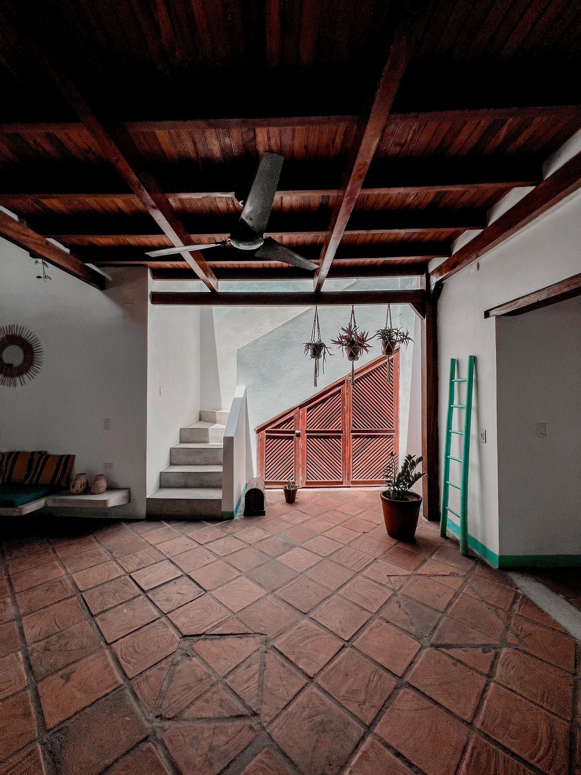 A room with a ceiling fan and stairs leading up to the second floor.