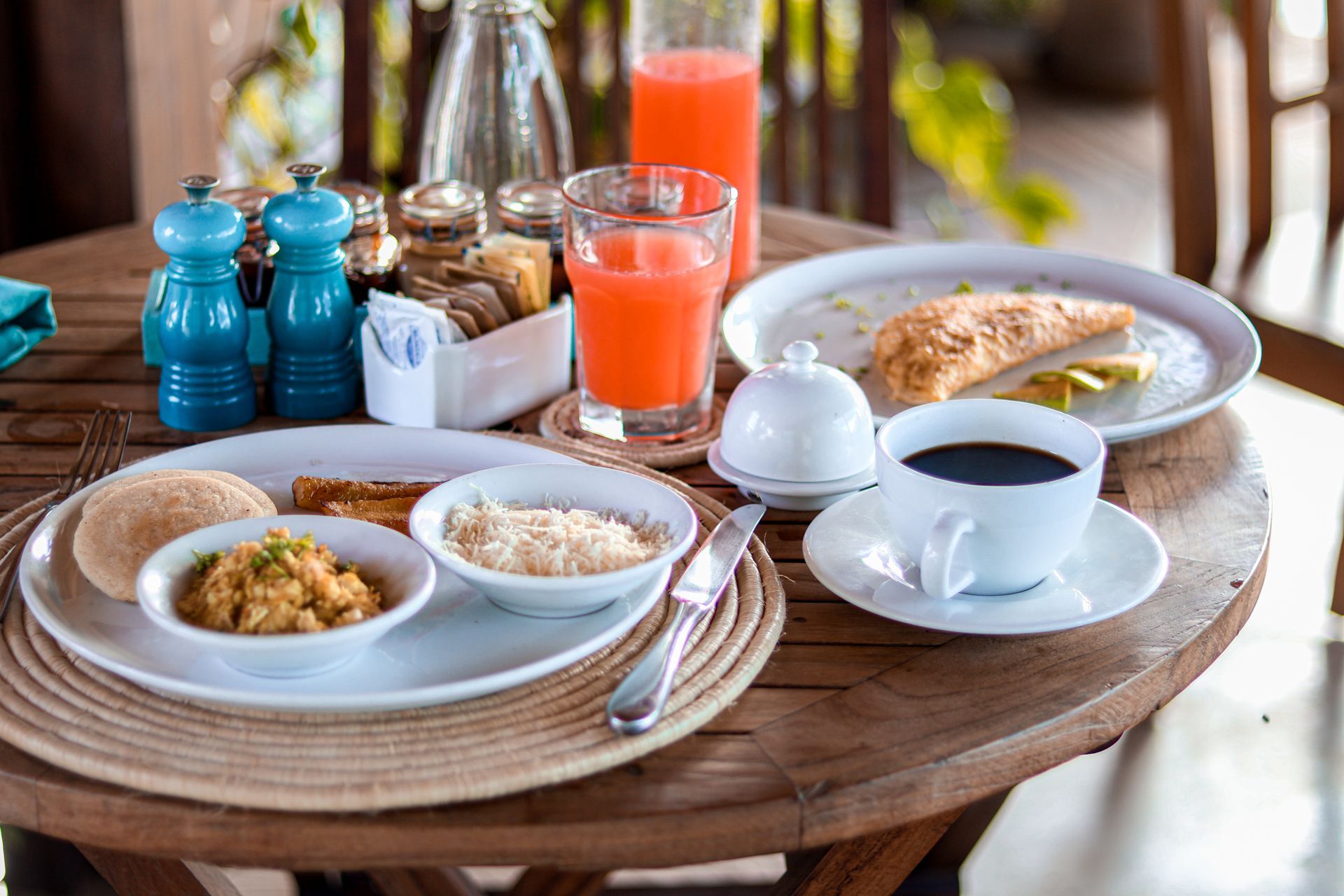A wooden table topped with plates of food and drinks.