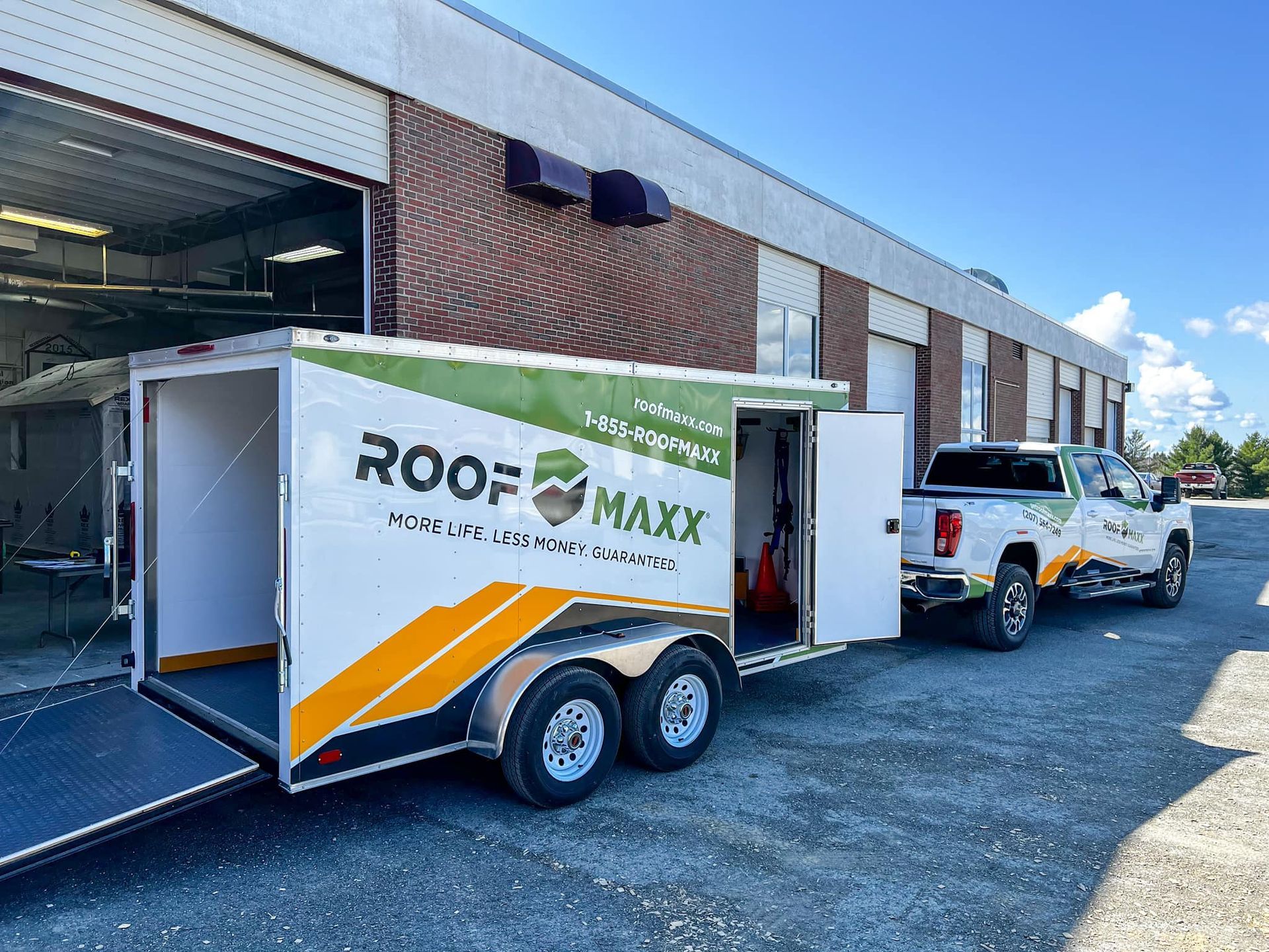 A trailer with the word roof maxx on it is parked in front of a building.