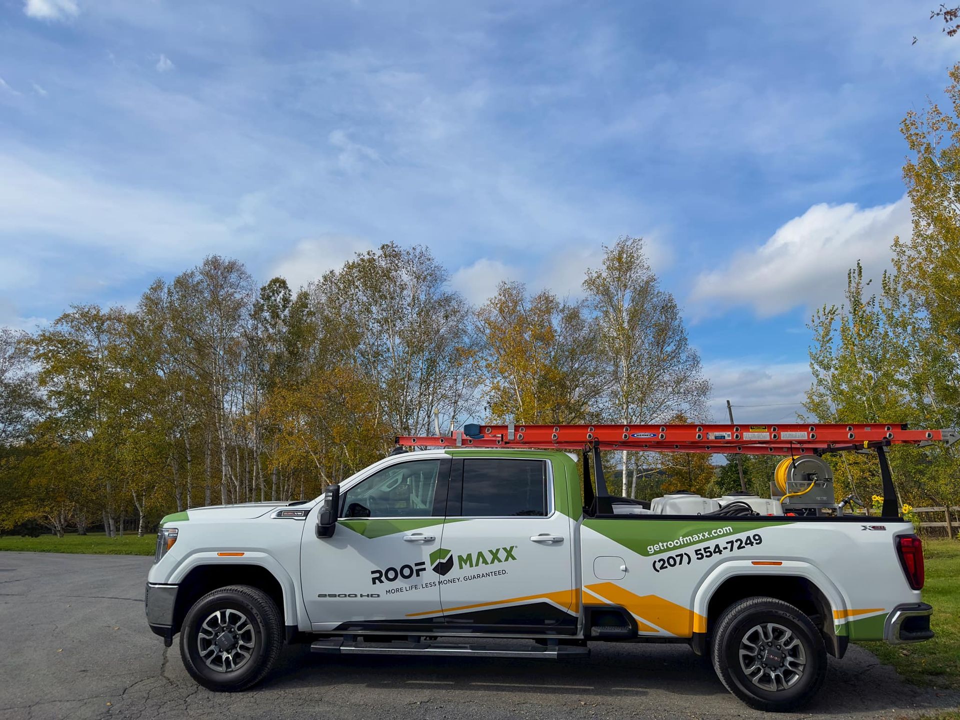 A white truck with a red ladder on top of it is parked on the side of the road.