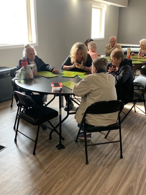 a group of people sit around a table playing bingo