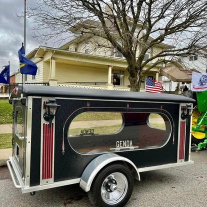 a black funeral trailer is parked in front of Day & Genda Funeral Home Frankfort location .