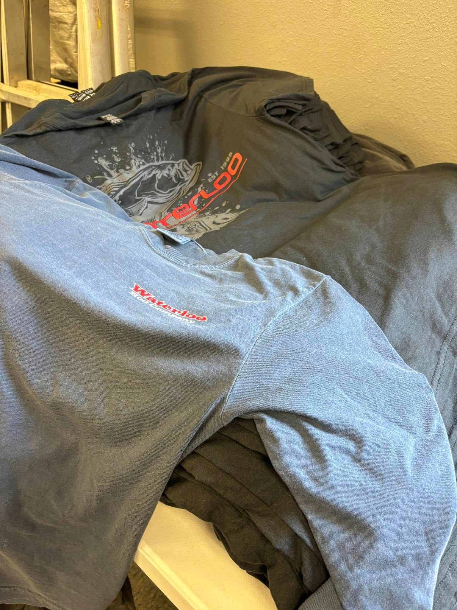 Pile of dark shirts, one with a red 