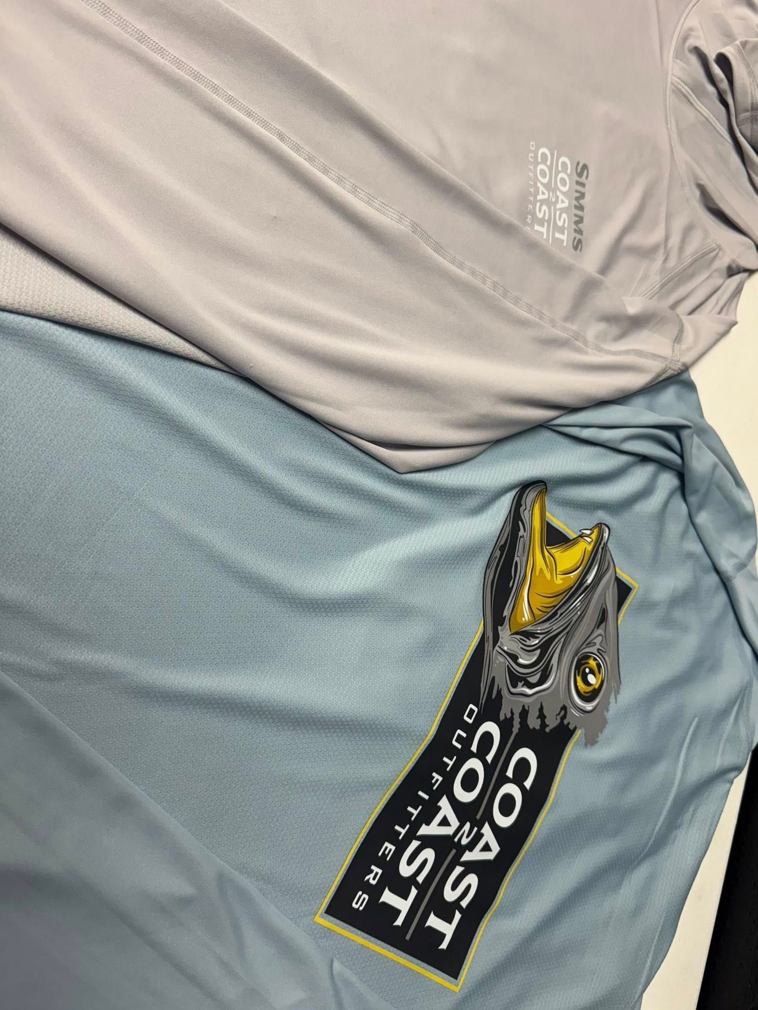 Two fishing shirts, gray and blue, with Coast 2 Coast Outfitters tag.
