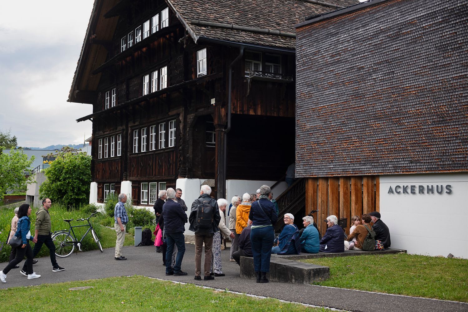 Das Ackerhus  mit modernem Anbau; Rasenfläche, Kiesweg, sonniger Tag.