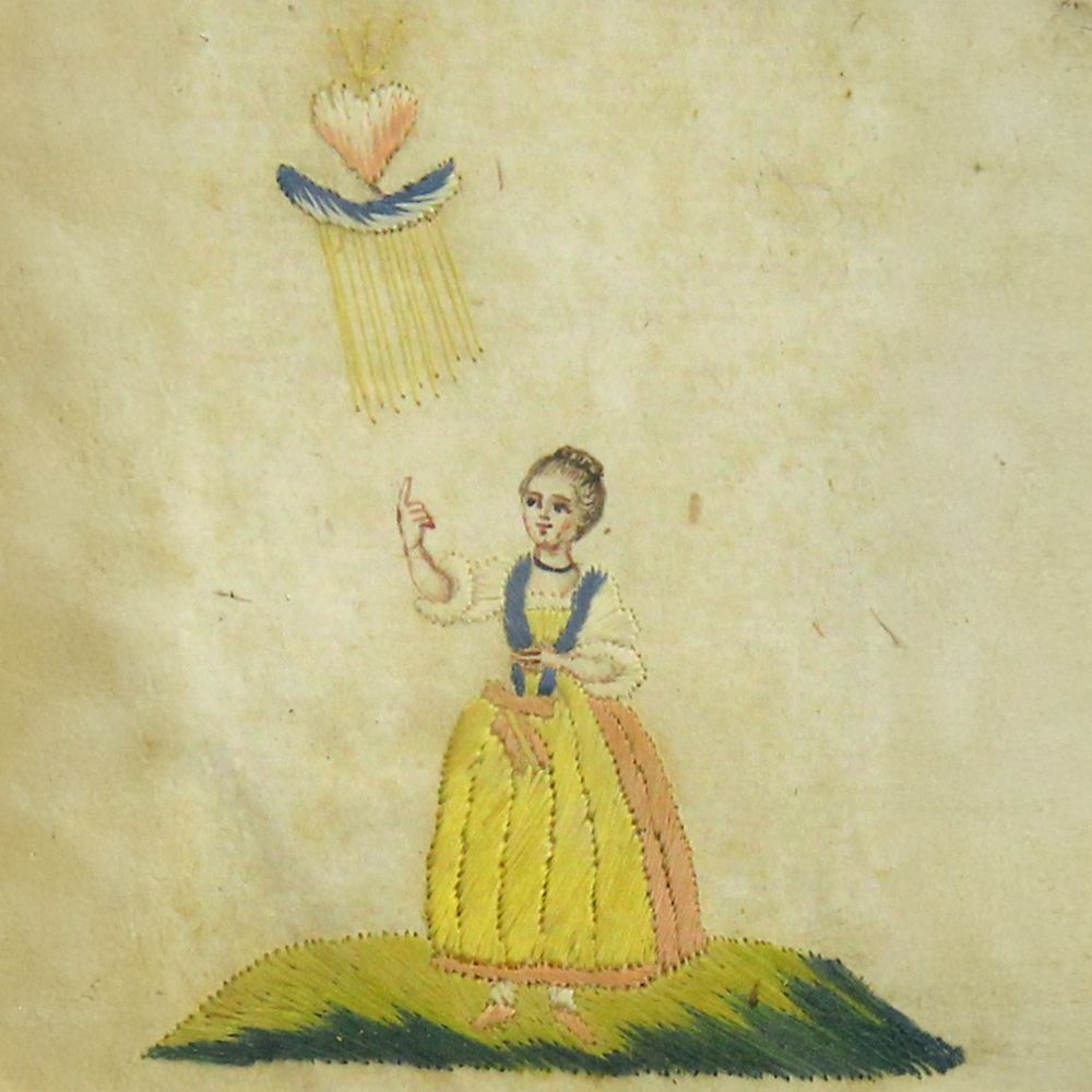 Gestickte Figur mit erhobener Hand unter einem strahlenden Herzen. Gelbes Kleid mit blauen und rosa Akzenten.